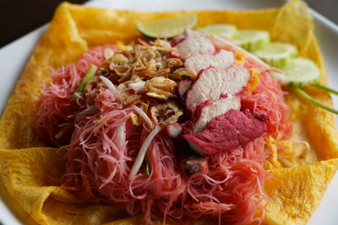Pad Mee Chomphu Moo Dang — pink vermicelli with red pork wrapped in a golden egg crêpe