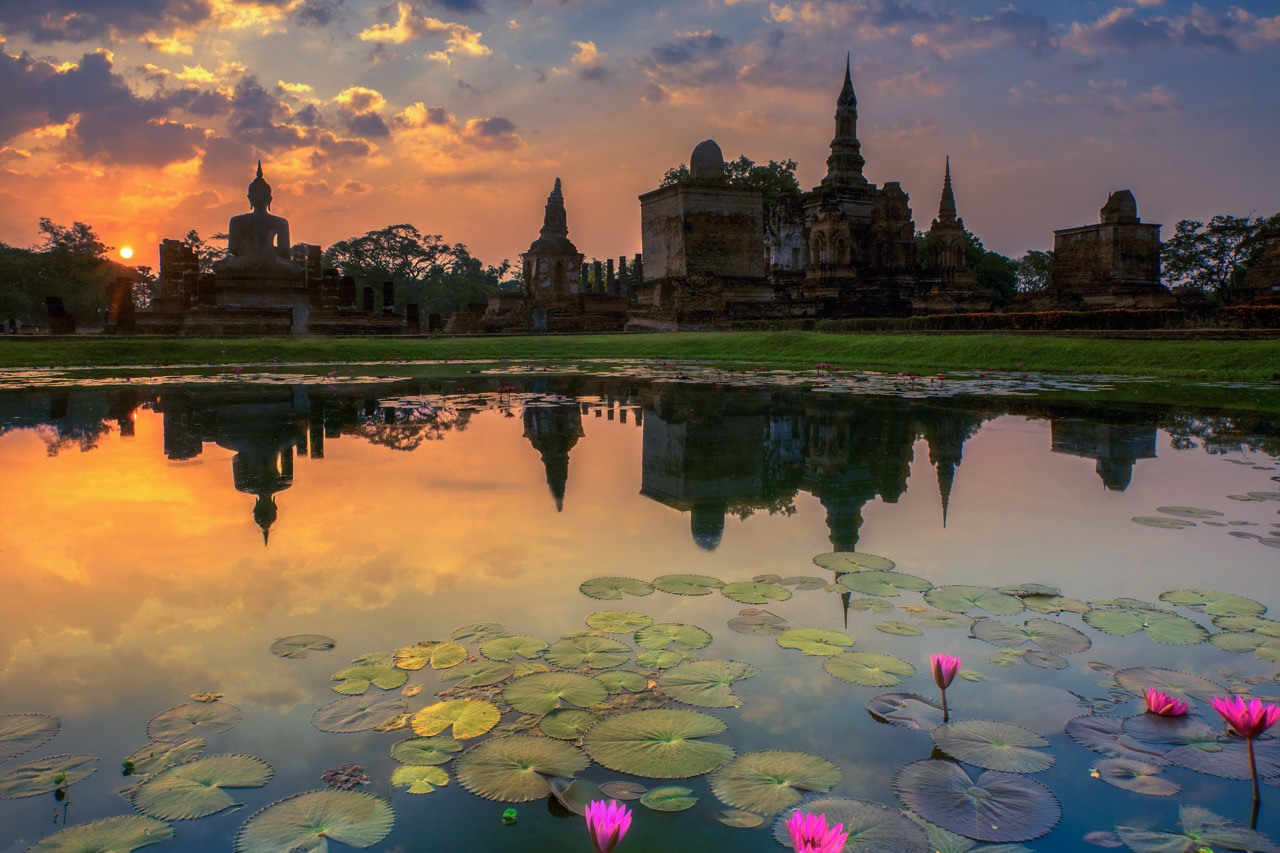 วัดหินโบราณในอุทยานประวัติศาสตร์สุโขทัยยามรุ่งอรุณ — แสงเช้าต่ำพาดผ่านสระบัว
