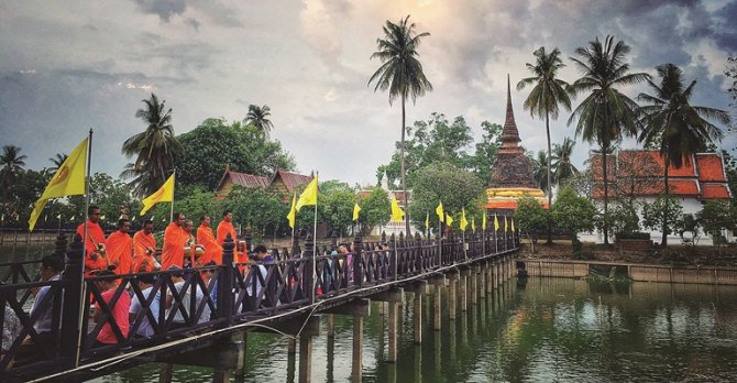 ขบวนตักบาตรยามเช้า — พระสงฆ์จีวรสีเหลืองเดินบนถนนเงียบสงบในสุโขทัยยามรุ่งอรุณ